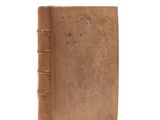 an old brown book sitting on top of a white surface
