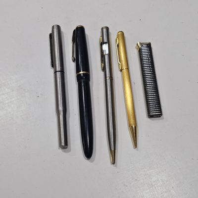 three pens and a comb are sitting on a white surface