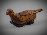 carved wooden bird on stand on grey background
