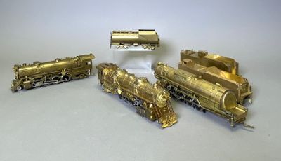 quatre types différents de trains en laiton posés sur une table