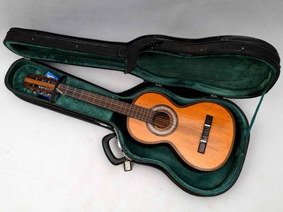 une guitare dans un étui, posée sur une surface blanche