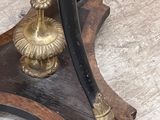a gold plate with a black handle on a wooden stand