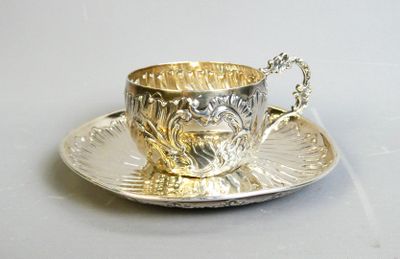 a silver cup and saucer sitting on a silver plate