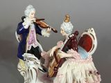 a figurine of a man playing a violin and a woman sitting on a bench
