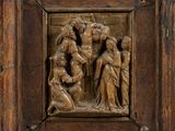 un vieux cadre en bois sur lequel est sculpté un groupe de personnes