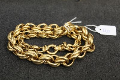 gros plan d'un bracelet en chaîne en or sur une surface noire