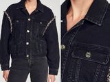 a woman wearing a black denim jacket with chains on the sleeves