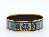 a close up of a blue and gold bracelet on a white surface