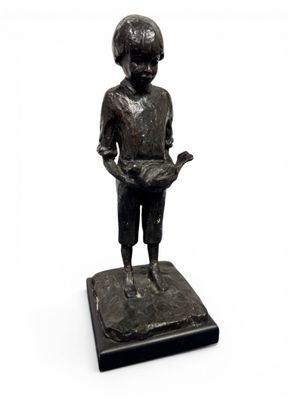 statue d'un garçon tenant un livre dans ses mains, posée sur un socle noir