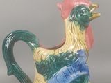 un petit pichet orné d'un coq, posé sur une table