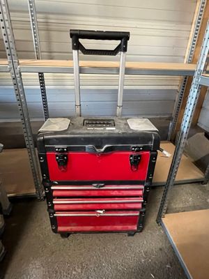 a red and black tool box with wheels in a garage