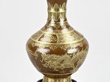 a brown vase with gold designs on it on a stand