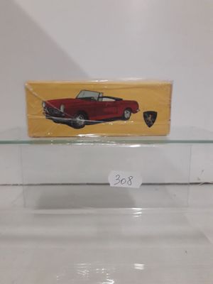 a red toy car on a glass shelf with a yellow box
