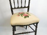 une petite chaise dont le dossier est orné d'un motif floral