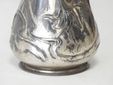 a silver vase with a face on it on a white surface