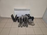 Plusieurs paires de bottes sont alignées contre un mur, près d'un radiateur.