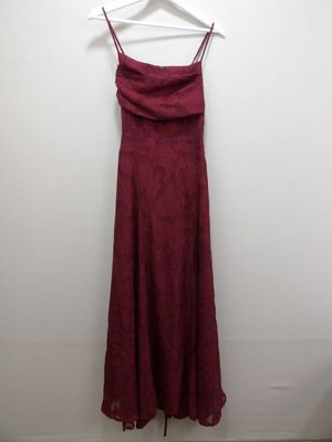 a red dress hanging on a hanger against a white wall