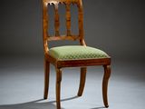 an antique wooden chair with green upholstered seat in a dark room
