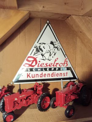 two toy tractors on a shelf with a sign above them