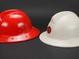 two red and white hard hats sitting side by side on a black background