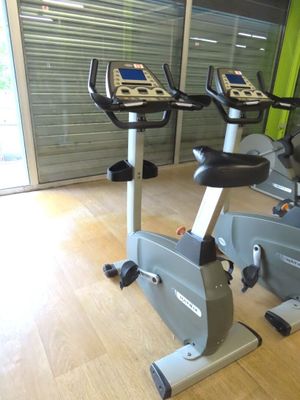 two stationary exercise bikes in a gym room with a sliding glass door