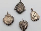 four silver pendants of various shapes and sizes on a white surface
