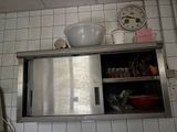 un placard en acier inoxydable dans une cuisine, avec une horloge accrochée au mur