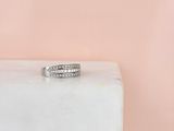 un gros plan d'une bague en diamant posée sur un bloc de marbre blanc