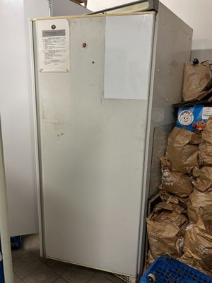 un réfrigérateur blanc au milieu d'une pièce remplie de cartons