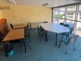 des tables et des chaises dans une pièce dotée d'une grande fenêtre donnant sur un parking