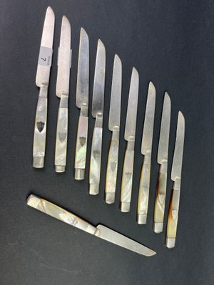 several knives are lined up on a table with a knife in front of them
