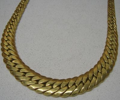 une photo d'un collier en or posé sur une surface blanche
