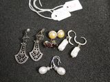 five pairs of earrings and a necklace on a table