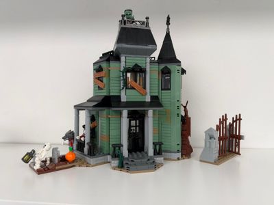 une maison verte avec un toit noir et une porte noire