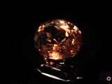 a close up of an orange diamond on a black surface
