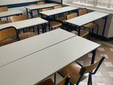 tables and chairs in an empty classroom with a window in the background