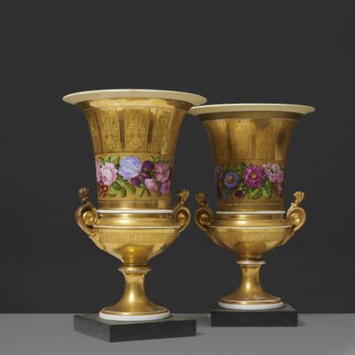 une paire de vases en or ornés de motifs floraux, posés sur un socle