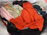 a pile of clothes in a plastic bag on a bed