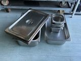 several pans of food are sitting on the floor in front of a shelf