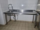 a stainless steel sink in the middle of a tiled room