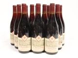 six bottles of wine are lined up in a row on a white surface