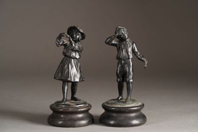 pair of bronze figurines of a boy and a girl on pedestals
