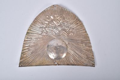 une assiette en argent sur laquelle est représenté un visage, sur un fond blanc