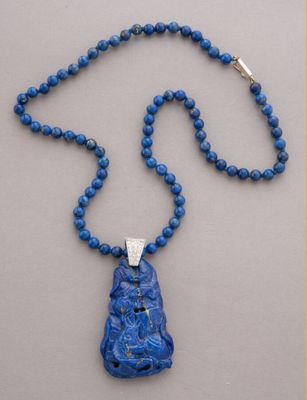 collier composé de perles bleues et d'un pendentif muni d'un fermoir en argent, sur fond gris
