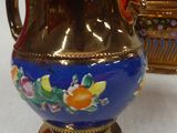 a blue and gold vase and a gold vase on a white table
