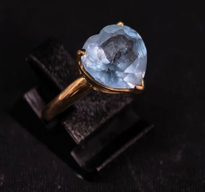 une bague en or sertie d'une topaze bleue sur un fond noir