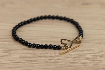 un gros plan d'un bracelet muni d'un fermoir en or posé sur une table en bois