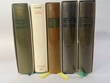 four books are lined up in a row on a white surface