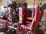 a red tractor with a plow attached to it in a barn