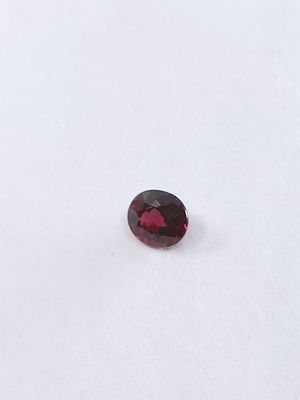 un gros plan d'une pierre de grenat rouge sur une surface blanche